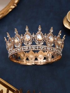 Close-up of golden crown with champagne rhinestones on blue velvet background