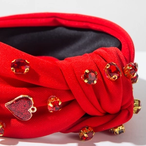 Nahaufnahme eines roten Knotenstirnbands mit Strasssteinen und Glitzerherz-Anhänger