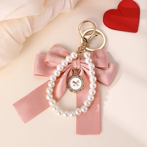 Detailed view of a pink bow keychain with imitation pearls and a rhinestone charm