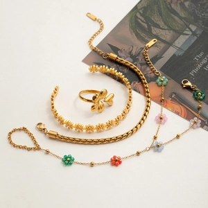 Detailed close-up of gold-plated flower ring and assorted beach-style bracelets set