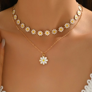 Detail of layered gold daisy necklace featuring white petal pendants on a female model