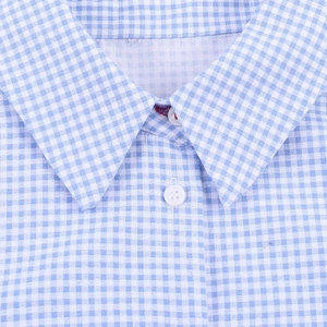 Macro detail of blue gingham fabric texture and white resin buttons on the V-neck shirt