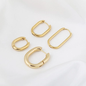 Polished gold U-shaped stainless steel earrings set on white fabric backdrop
