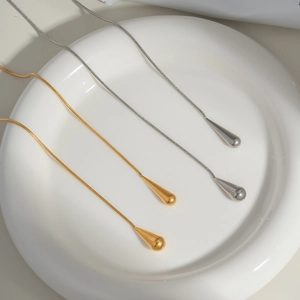Élégantes boucles d'oreilles pampilles gouttes or et argent sur plateau blanc