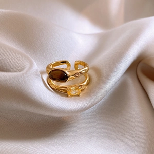 Macro detail of 18k gold plated tiger eye ring with faceted zircon on champagne silk