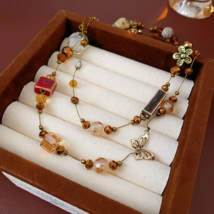 Vue macro détaillée du collier en perles de céramique avec papillon doré et fleurs
