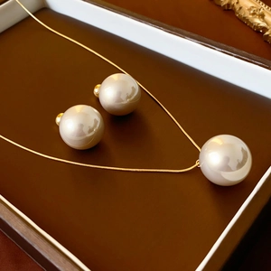 Macro shot of gold plated pearl necklace and matching stud earrings in a jewelry box