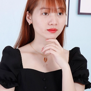 Gros plan du pendentif feuille dorée avec ambre et boucles d'oreilles assorties sur mannequin