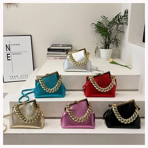 Detailed view of colorful metallic chain handbags displayed on minimalist white stairs