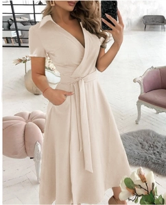 Dettaglio ravvicinato dello scollo a V e della cintura sulla veste beige a maniche corte