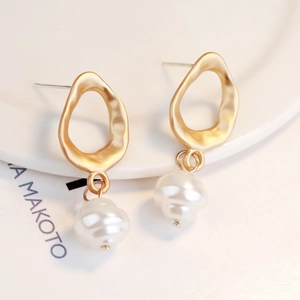 Detail view of vintage baroque irregular pearl earrings with a matte gold wavy metal frame