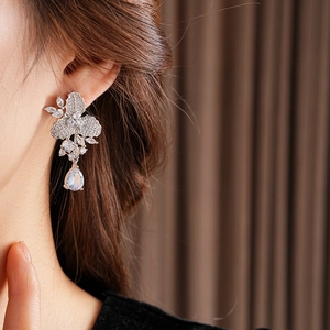 Elegante silberne Ohrringe mit Blumen- und Blattmotiven und Zirkon-Tropfen am Model