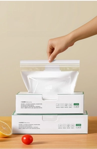 Detail view of food-grade storage bags being pulled from a box on a wooden table