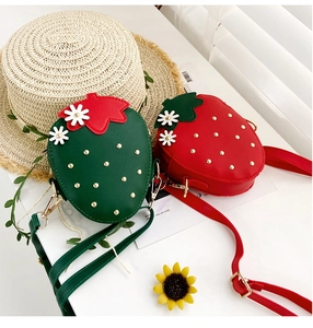 Detail of red and green strawberry crossbody bags with gold studs and floral accents