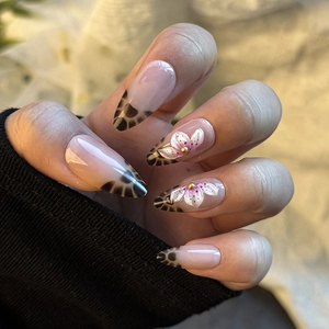 Détail macro de faux ongles amande avec fleurs 5D en relief et motifs léopard chic