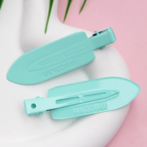 Close-up of mint green duckbill hair clips with matte finish and non-slip stripes on tray