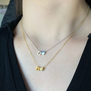 Close-up of gold and silver S925 necklaces with D-letter and heart pendants on model