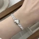 Gros plan d'un charme en forme de cœur sur un bracelet à maillons en acier titane argent
