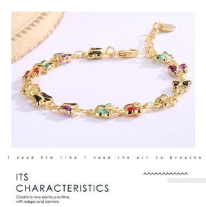 Detail of a gold butterfly bracelet with colorful enamel charms in a magazine layout