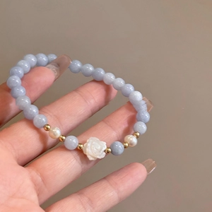 Detail view of Shoushan stone bracelet featuring blue beads and a white resin rose charm
