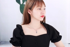 Close-up of a model wearing a minimalist silver heart-shaped key pendant necklace