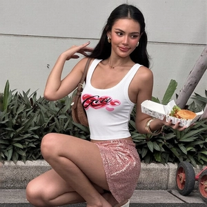 Photo en extérieur d'un mannequin portant un débardeur blanc et une mini-jupe à paillettes