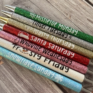 Detail of Christmas glitter pens with festive phrases on a rustic wood background
