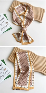 Close-up of mustard yellow silk twilly scarf with monogram pattern and white border