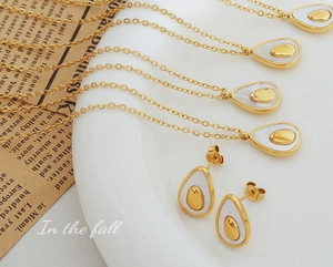 Detail view of avocado-shaped gold jewelry set with white shell inlay on a vintage base