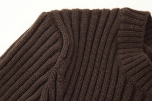 Vue macro détaillée d'un pull en maille côtelée marron foncé montrant la couture de l'épaule
