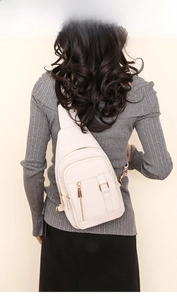 Rear view of cream PU leather sling bag with three zippered layers and gold hardware