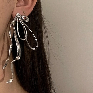 Close-up of silver bow ribbon earrings with clear stone on a female ear model