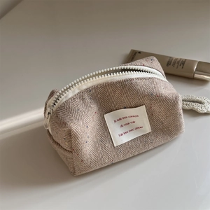 Detail of herringbone wool cosmetic bag with colorful specks and white chunky zipper