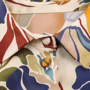 Détail du col à revers avec imprimé abstrait et boutons recouverts sur chemise en satin