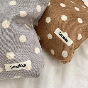 Close-up of retro polka dot corduroy cosmetic bags in grey and brown with woven labels