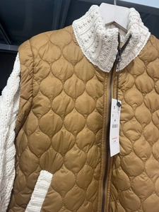 Detail view of quilted brown vest with white knit collar and metal zipper closure