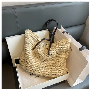 Detail of hand-woven straw tote bag in premium gift box with brown leather straps