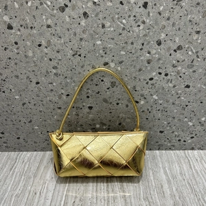 Detailed view of golden woven leather texture and knot handle on a small square bag