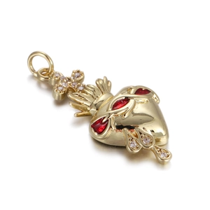 Detailed view of a golden Sacred Heart cross pendant with red and clear gemstones