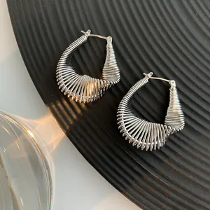 Detail view of silver twisted U-shaped hoop earrings with horizontal rippled texture