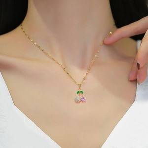 Gold cherry necklace with pink crystals and green leaves on an elegant female model