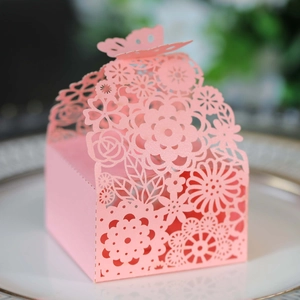 Macro shot of laser-cut pink gift box with floral patterns and butterfly closure on a plate
