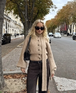 Outdoor street view of cable knit cardigan set with matching scarf in oatmeal color