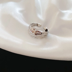 Close-up of a silver multi-layer braided open ring on elegant white satin fabric