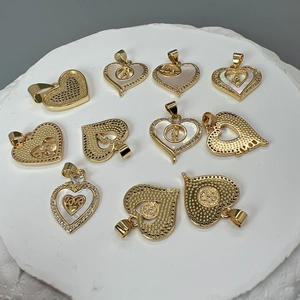 Flat lay of ten golden heart-shaped pendants with mother of pearl and zircon details