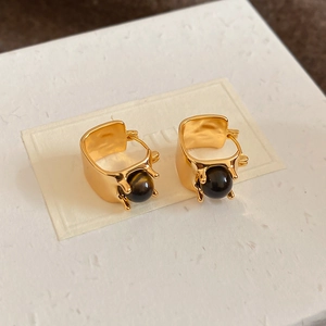 Detailed close-up of gold-plated wide hoop earrings with brown tiger eye stone spheres