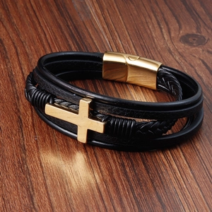 Detail of multi-layer black leather bracelet with golden cross and magnetic clasp
