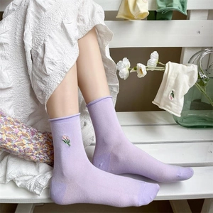 Soft cotton crew socks in purple with floral embroidery on white wooden background
