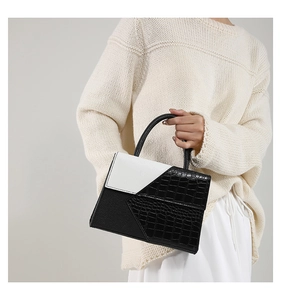 Détail de la texture crocodile noir et cuir blanc sur un petit sac à main carré chic