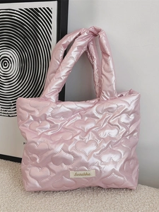 Borsa a mano trapuntata rosa con motivo a cuori e etichetta su un tappeto